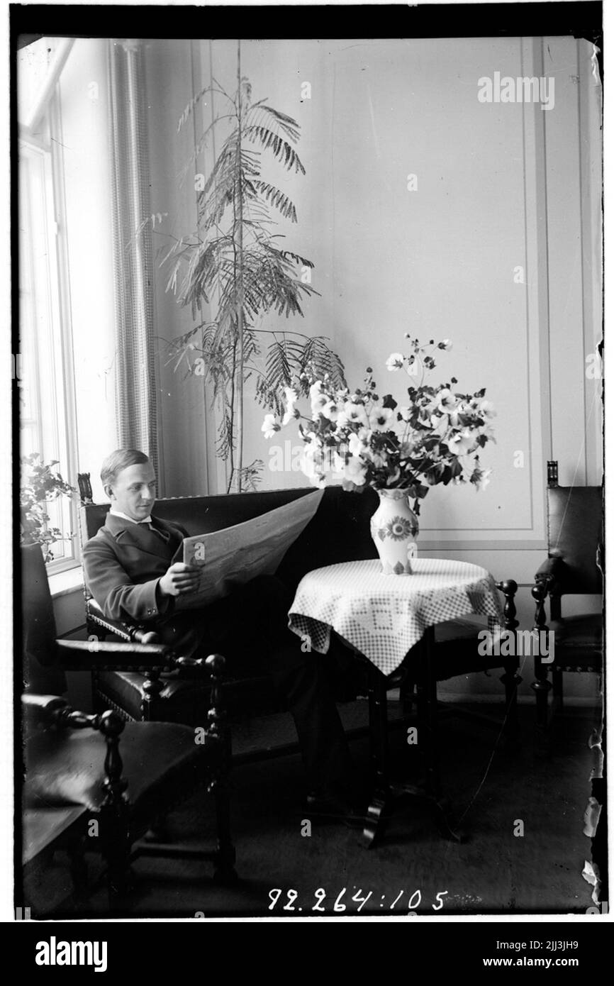 Hålahult Sanatorium, innen, sitzt ein Mann auf einem Sofa an einem Tisch und liest die Zeitung. Stockfoto