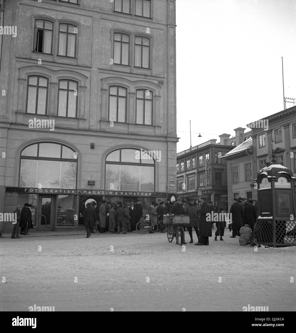 Die Hindernismesse in Örebro am 26. Januar 1937. Neben dem großen Hotel, gleich neben der Kreuzung zwischen Engelbrektsgatan und Drottninggatan, versammelten sich Menschen. Im Erdgeschoss des Hotelgebäudes befindet sich ein Fotoladen. Ein wenig weiter auf der Drottninggatan können Sie ein Geschäftsschild mit dem Namen Oscaria sehen. Dies ist höchstwahrscheinlich ein Schuhgeschäft, da Oscaria der Name einer der größten Schuhfabriken von Örebro war. Ganz rechts befindet sich ein altmodisches Telefonkabinen. Stockfoto