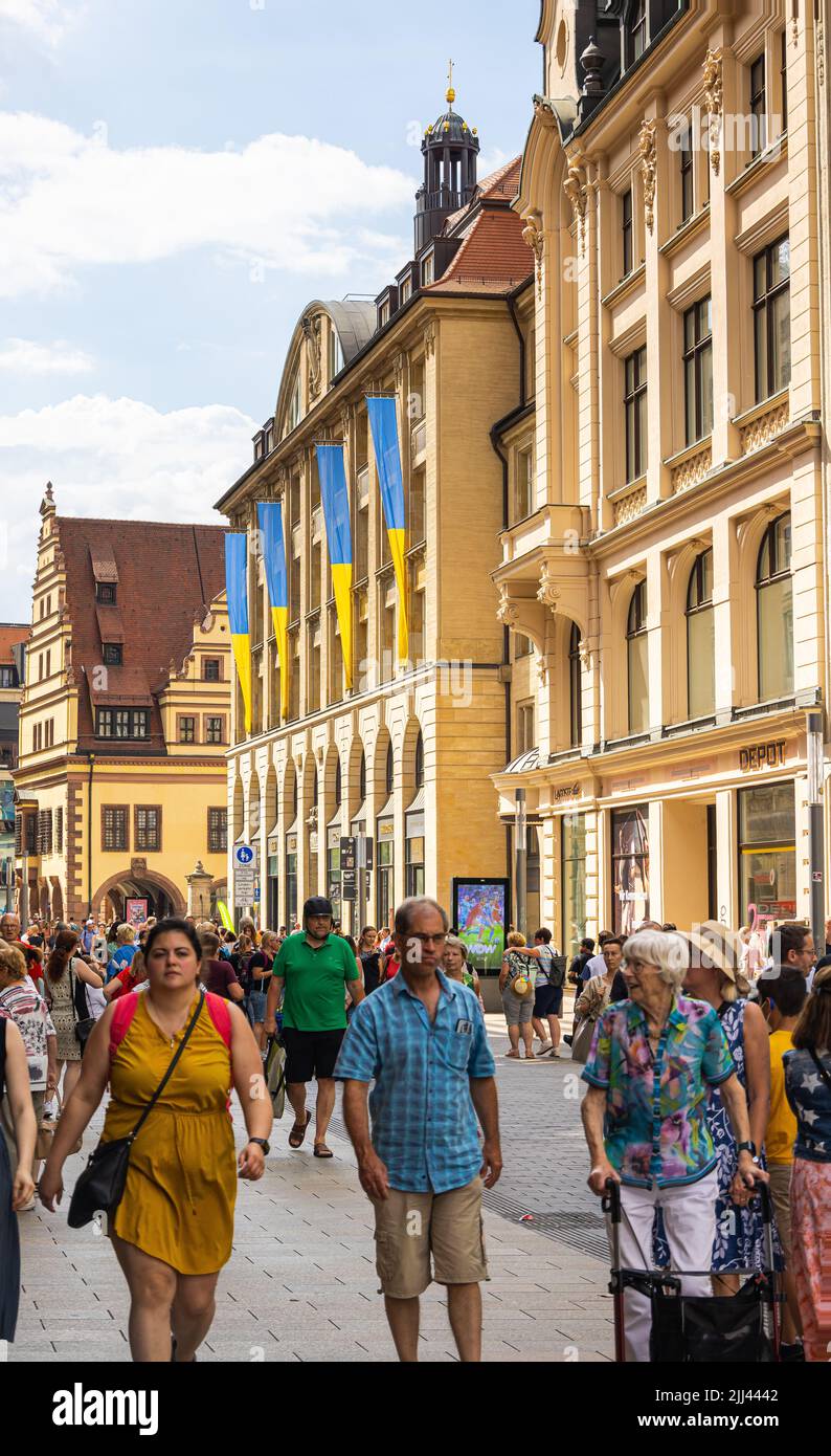 Leipzig, Deutschland - 25. Juni 2022: Blick auf die Grimmaische Straße. Touristen und Einheimische bummeln über die Straße mit vielen Geschäften. Blue und yel Stockfoto