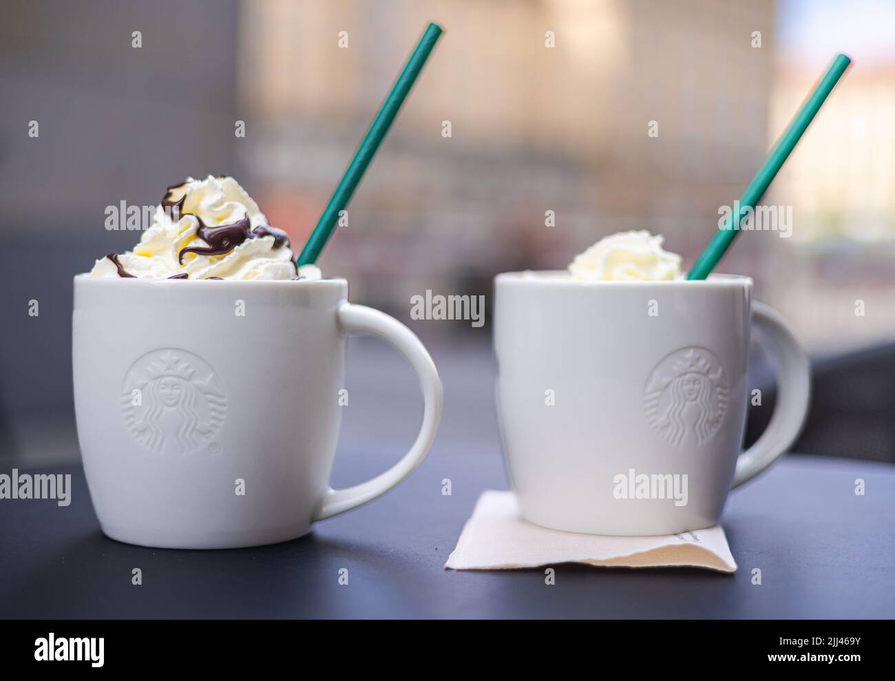 Dresden, 28. Juni 2022: Zwei Starbucks Kaffeetassen mit grünem Stroh. Das süße Getränk mit Creme auf den Getränken. Kaffeetassen auf einem Tisch, Kappe Stockfoto