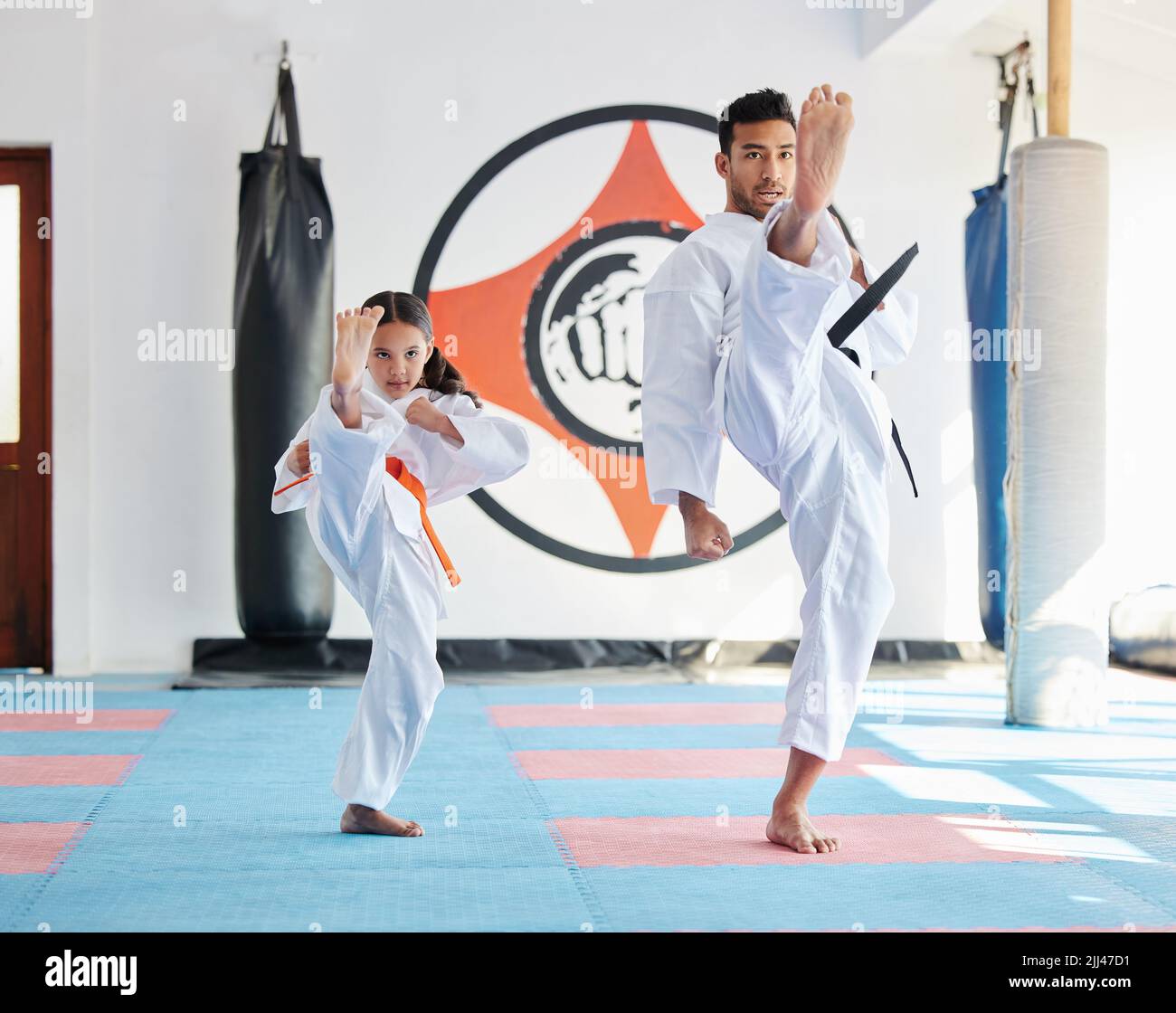 Lassen Sie sich nicht von ihrer Größe täuschen. Ein junger Mann und nettes kleines Mädchen üben Karate in einem Studio. Stockfoto