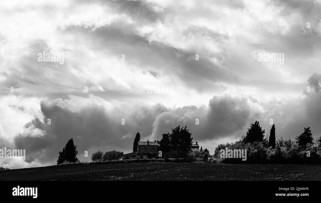 Dunkle Wolken über einem Landhaus, Schwarz-Weiß-Fotografie, bei Monticchiello, Toskana, Italien Stockfoto