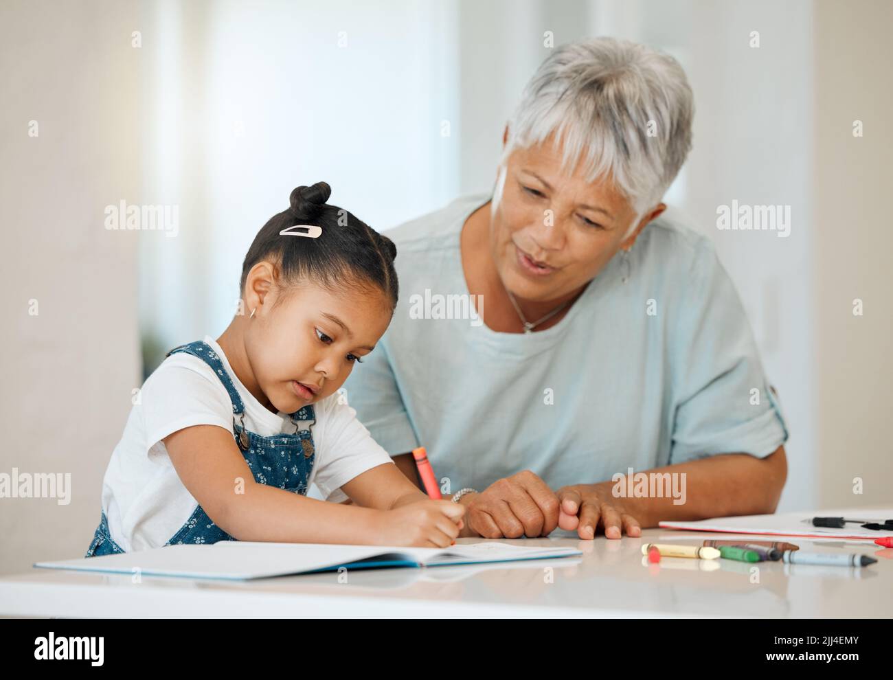 Das sind schöne Farben. Eine Oma hilft ihrer Enkelin am Küchentisch zu Hause. Stockfoto