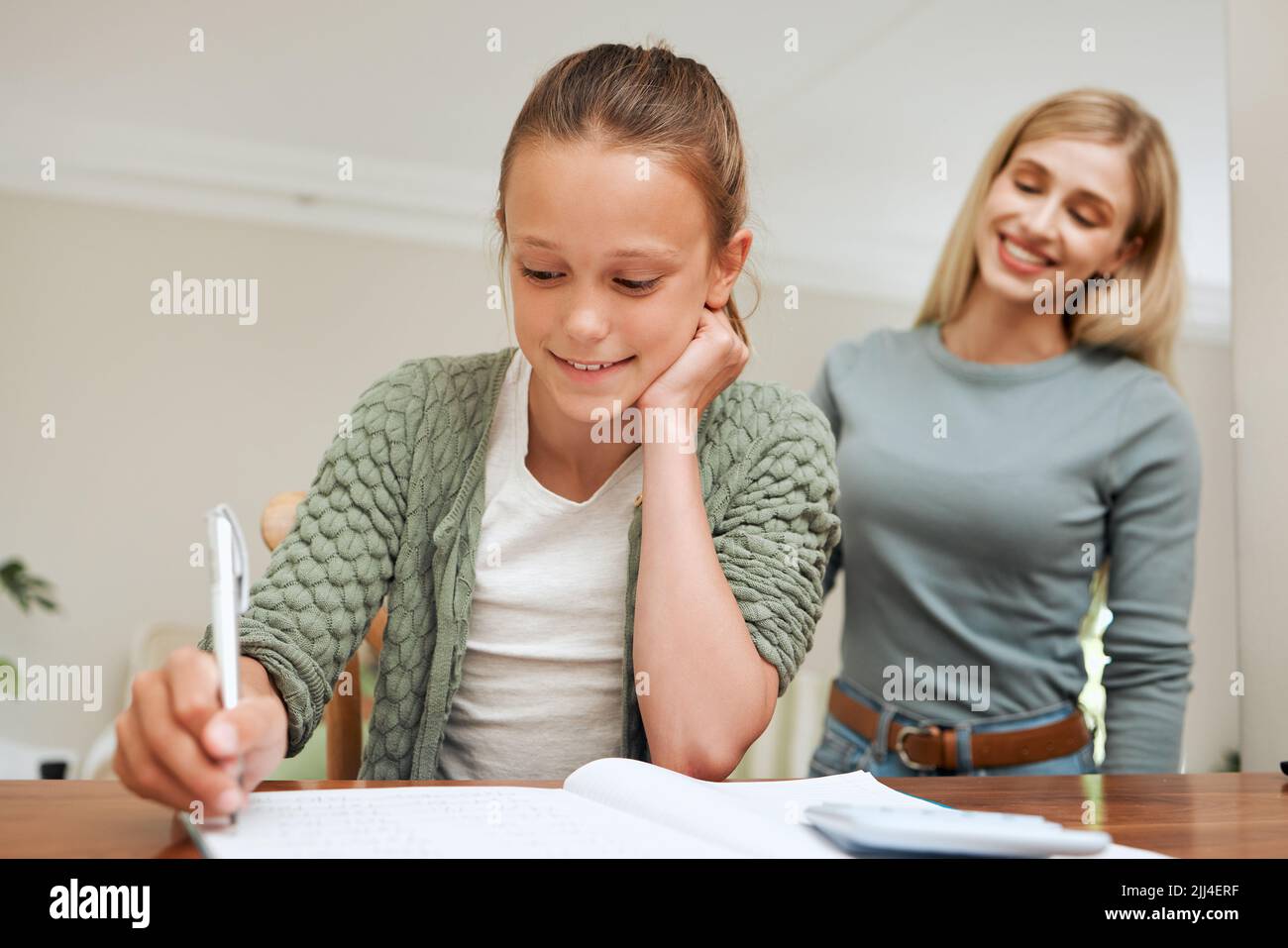 Ihre Zukunft ist gut. Eine Mutter hilft ihrer Tochter bei den Hausaufgaben am Küchentisch zu Hause. Stockfoto