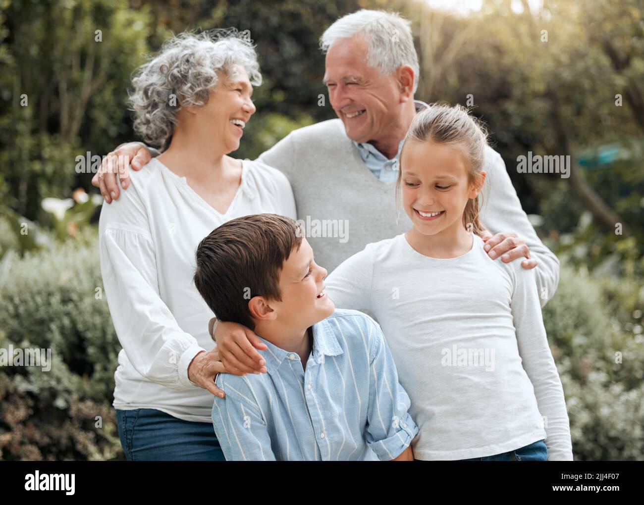 Wir lieben unsere Familie. Zwei Geschwister posieren für ein Bild mit ihren Großeltern draußen. Stockfoto