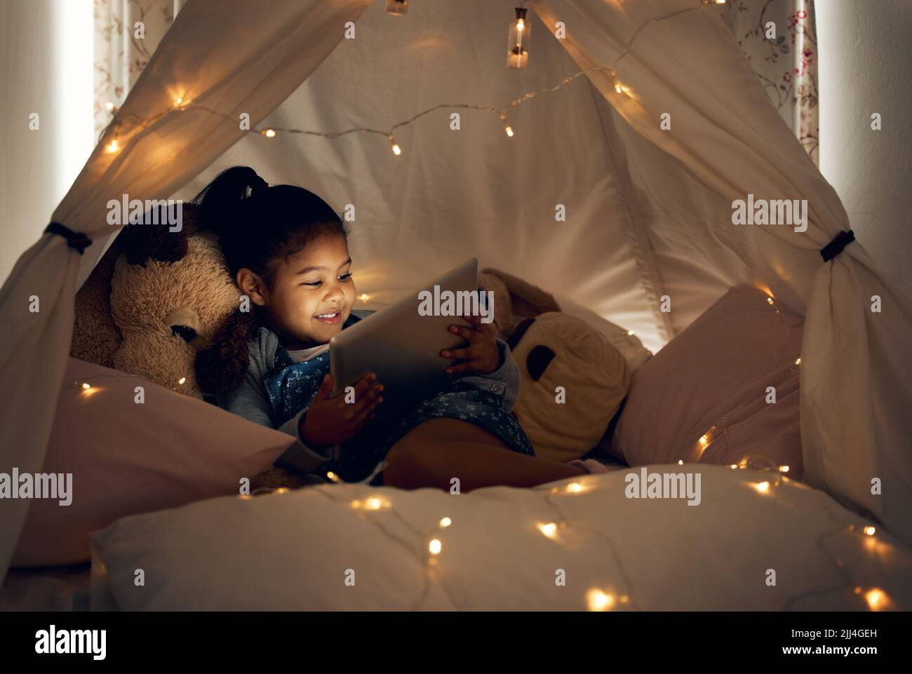 Shes bereit zum Entspannen. Ein kleines Mädchen mit einem digitalen Tablet spät in der Nacht zu Hause. Stockfoto