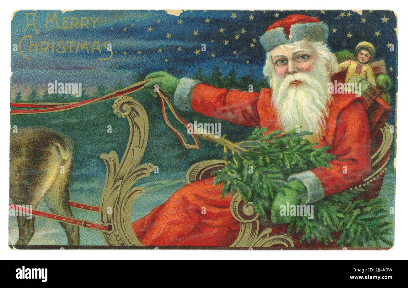 Die originale edwardianische Ära prägte die Weihnachtspostkarte des Weihnachtsmanns mit einem Sack Spielzeug, hielt einen Weihnachtsbaum in der Hand und fuhr in einer Nacht mit Sternenlicht in einem Schlitten, der von Rentieren gezogen wurde, um 1910 Stockfoto