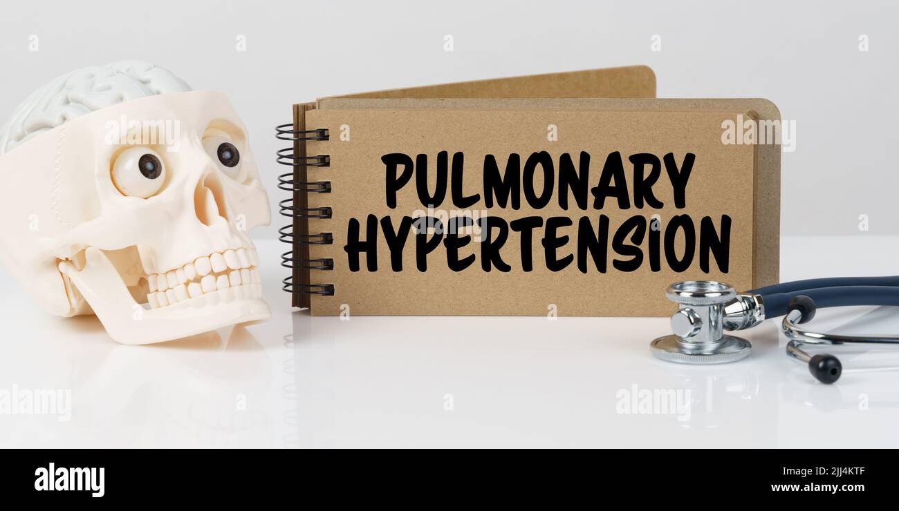Medizin und Gesundheitskonzept. Auf dem Tisch liegen ein Schädel, ein Stethoskop und ein Notizbuch mit der Aufschrift - PULMONALE HYPERTONIE Stockfoto