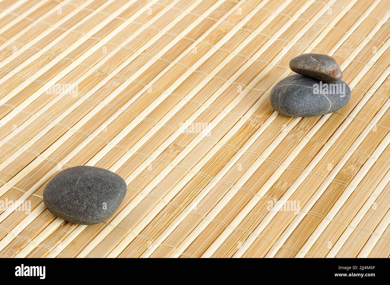 Bambus-Matte-Textur mit Zen-Kieselsteinen, babu-Hintergrund für Projekte, Ort für Text Stockfoto