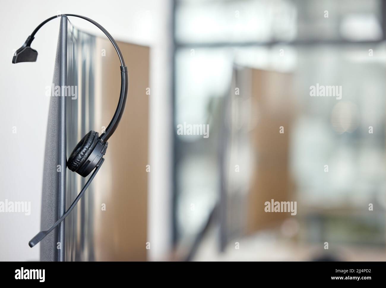 Zeichen eines harten Arbeiters ist jemand, der ohne Beschwerde arbeitet. Nahaufnahme eines Headsets, das in einem Büro auf einem Computerbildschirm hängt. Stockfoto