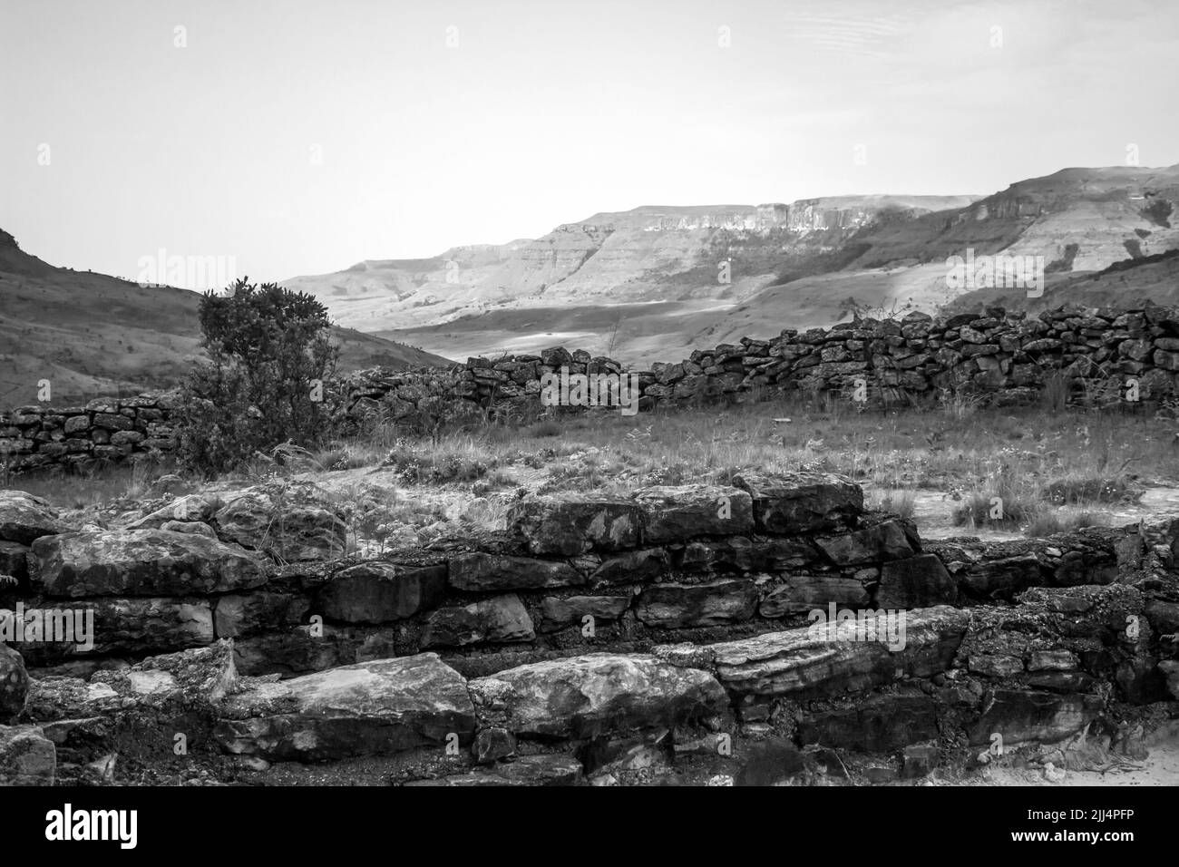 Die Ruinen eines alten verlassenen Tauchbecken für Rinder, mit den zerklüfteten südafrikanischen Drakensberg Mountains in schwarz-weiß Stockfoto