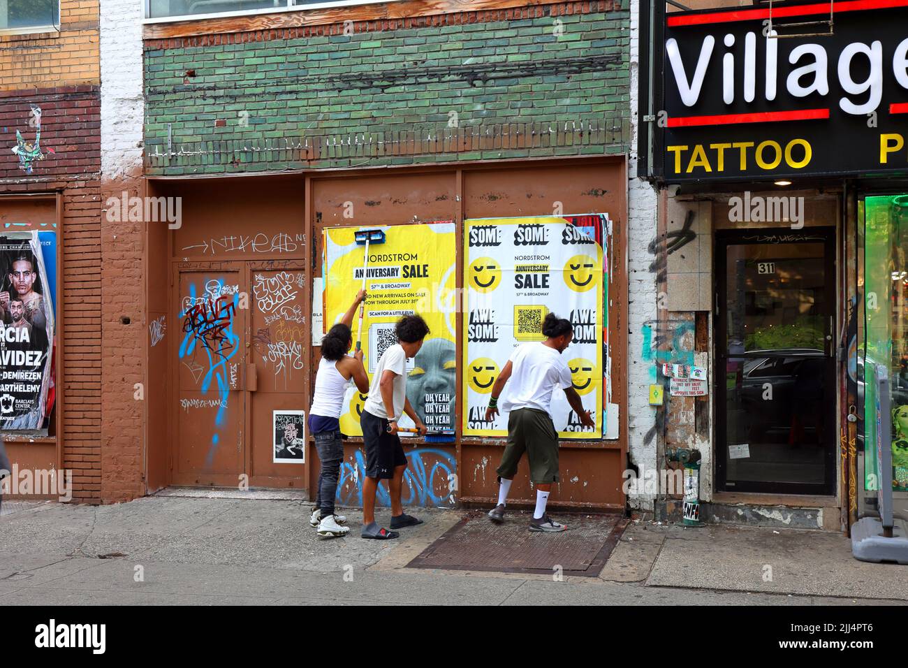 Menschen, die Werbeplakate an eine Wand kleben oder wild Werbeplakate posten, als Teil einer städtischen Marketing-Kampagne auf Straßenebene, Guerilla. Stockfoto