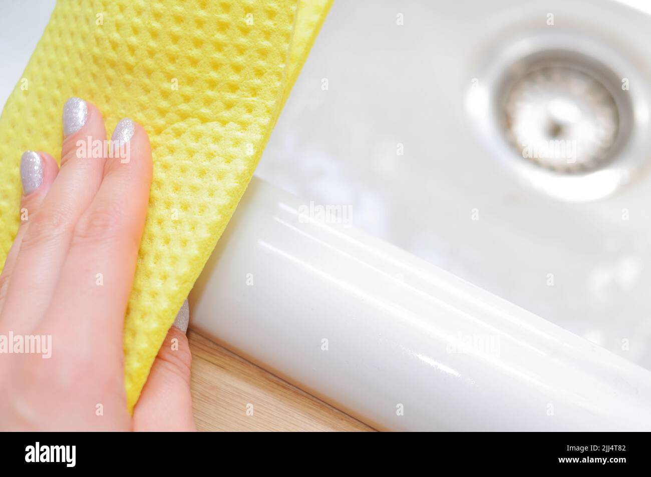 Nahaufnahme der Hand in blauen Handschuhen mit gelbem Lappen zum Abwischen von Schlamm, Reinigungskonzept, Hausaufgaben Stockfoto