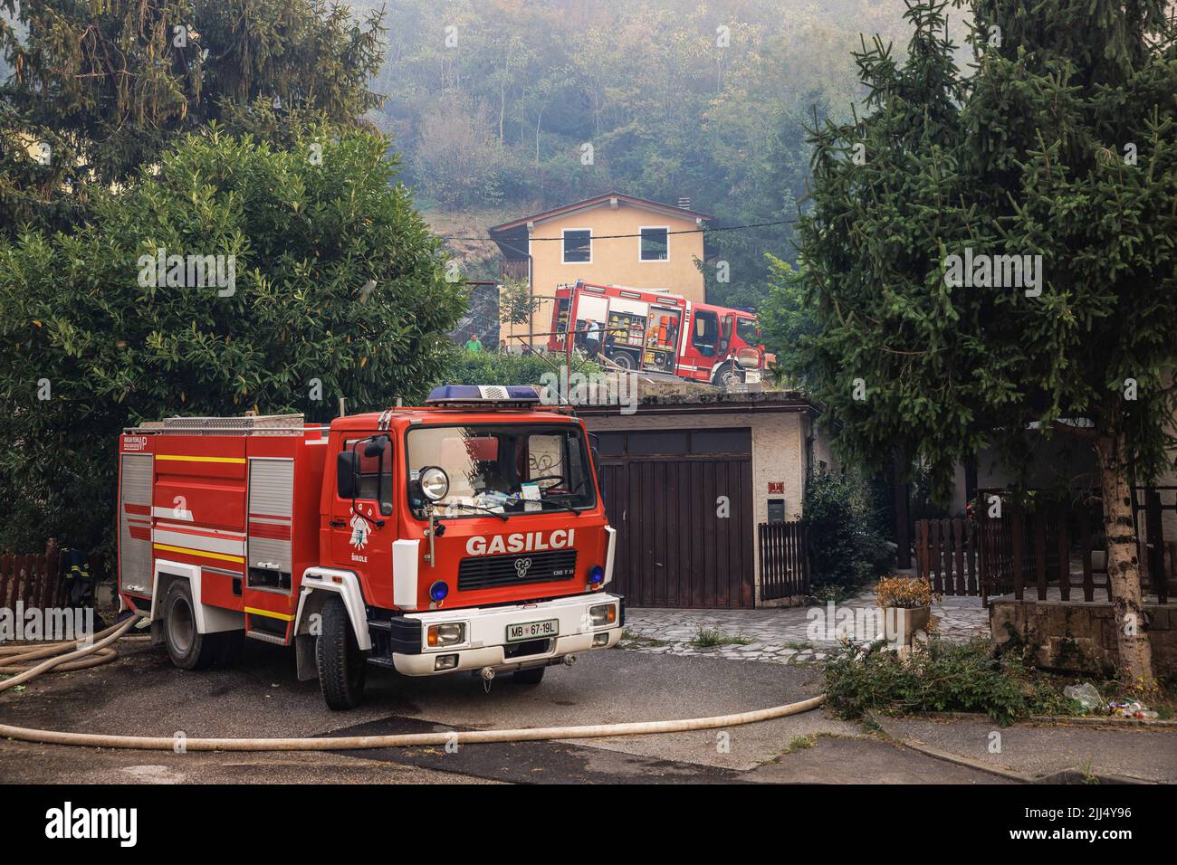 Karst, Slowenien. 22.. Juli 2022. Feuerwehrautos werden vor Häusern in Vrtoce geparkt, während Feuerwehrleute ein großes Waldfeuer in den Hügeln über dem Dorf bekämpfen. Etwa tausend Feuerwehrmänner mit Luftunterstützung von drei slowenischen Hubschraubern, zwei serbischen Hubschraubern, einem österreichischen Hubschrauber, einem slowakischen Black Hawk-Hubschrauber und zwei ungarischen Hubschraubern, Ein kroatisches Canadair-Löschflugzeug und ein Pilatus-Flugzeug der slowenischen Armee kämpften weiter gegen ein großes Waldfeuer, das vor fünf Tagen ausbrach und sich in der Karstregion Sloweniens verstärkt hat. Die Dörfer in der Umgebung wurden evakuiert. Dies ist die l Stockfoto