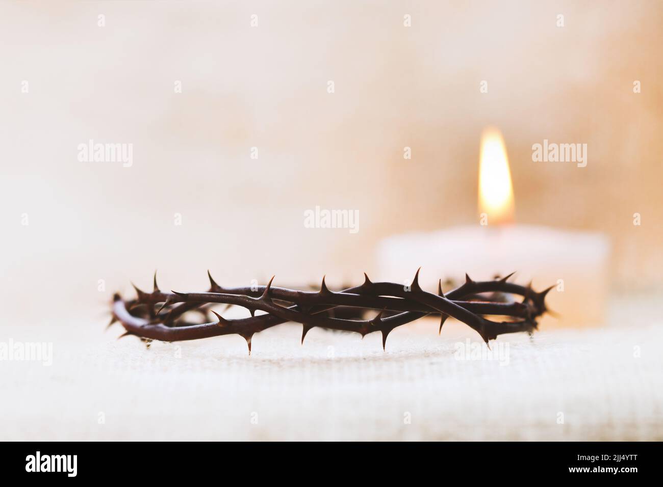 Dornenkrone, die das leidende Kreuz, den Tod und die Auferstehung Jesu Christi und den hell leuchtenden Kerzenhintergrund symbolisiert Stockfoto