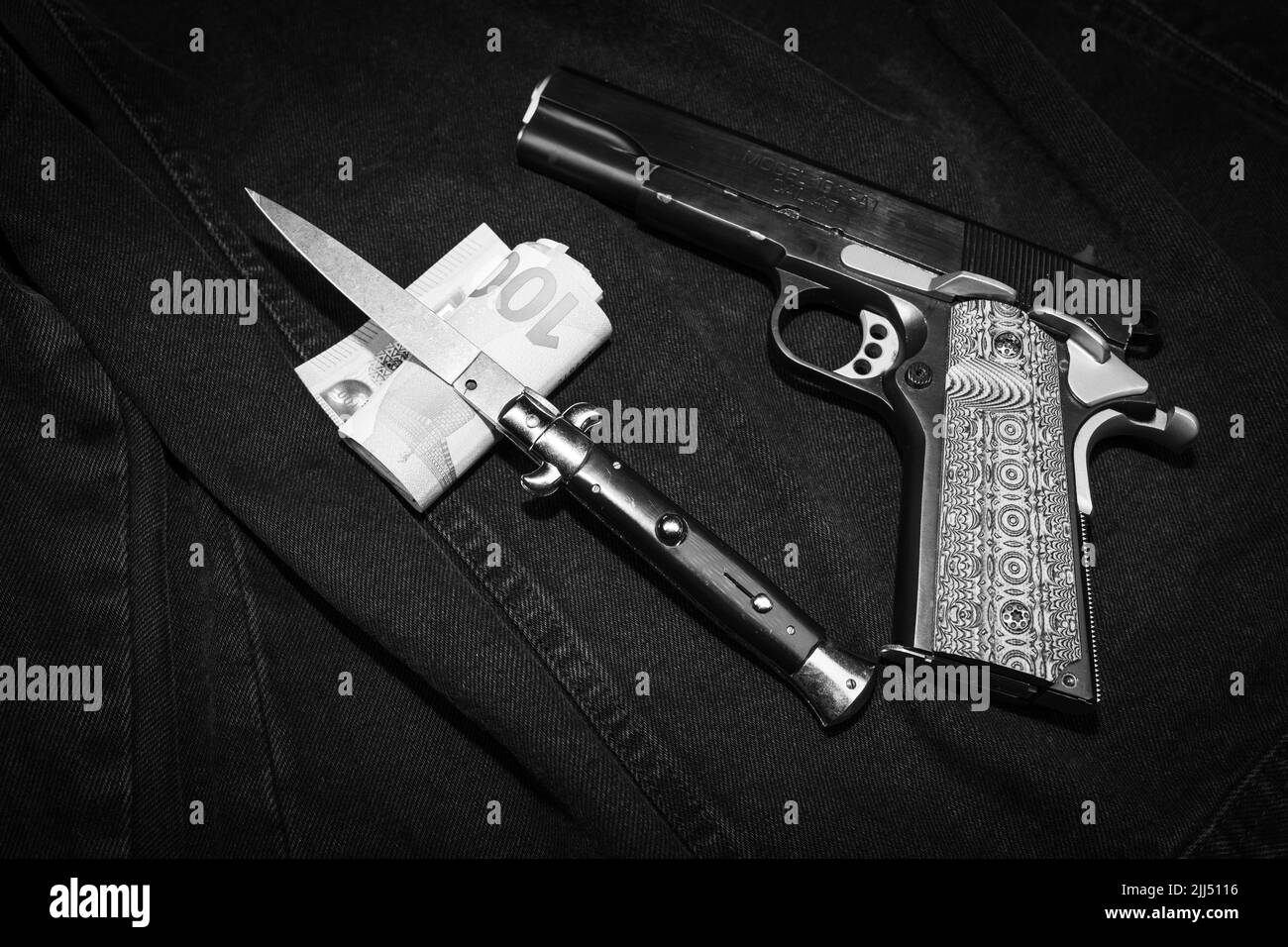 Ein italienisches Messer, eine Geldscheinrolle und eine Pistole mit dekorativem Griff, monochromes Foto Stockfoto