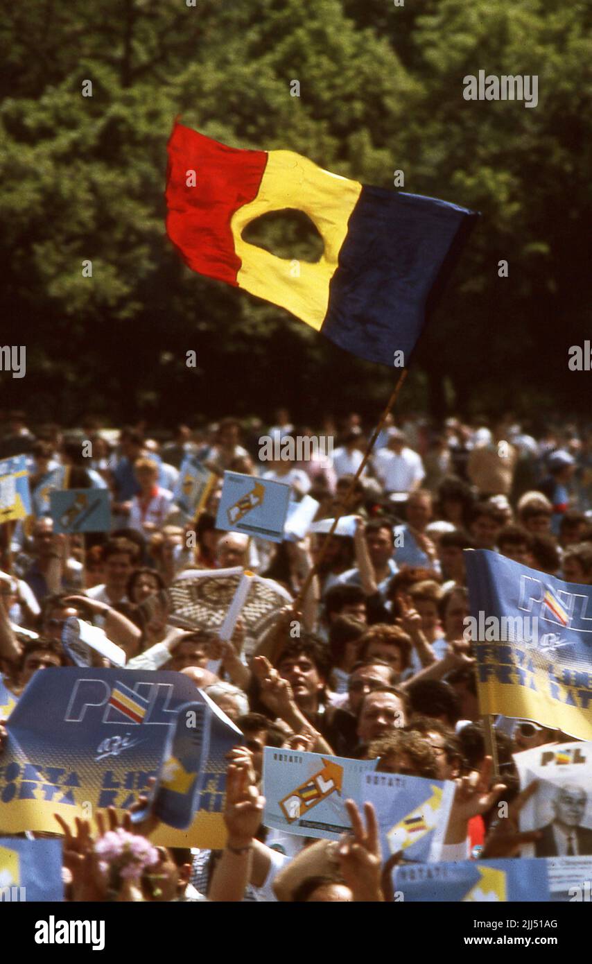 Bukarest, Rumänien, Mai 1990. Politische Kundgebung, die von der Nationalen Liberalen Partei (PNL) Tage vor den ersten demokratischen Wahlen nach dem Fall des Kommunismus organisiert wurde. Person, die die rumänische Flagge schwenkt und das sozialistische Emblem abgeschnitten hat, ein antikommunistisches Symbol während der rumänischen Revolution von 1989. Stockfoto