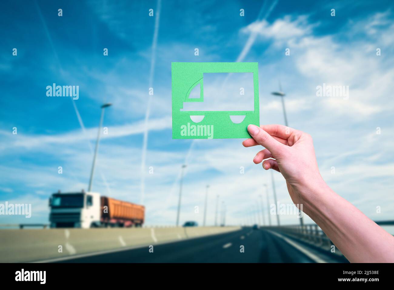 Hand hält grünes Logistik-Symbol gegen Autobahn Stockfoto