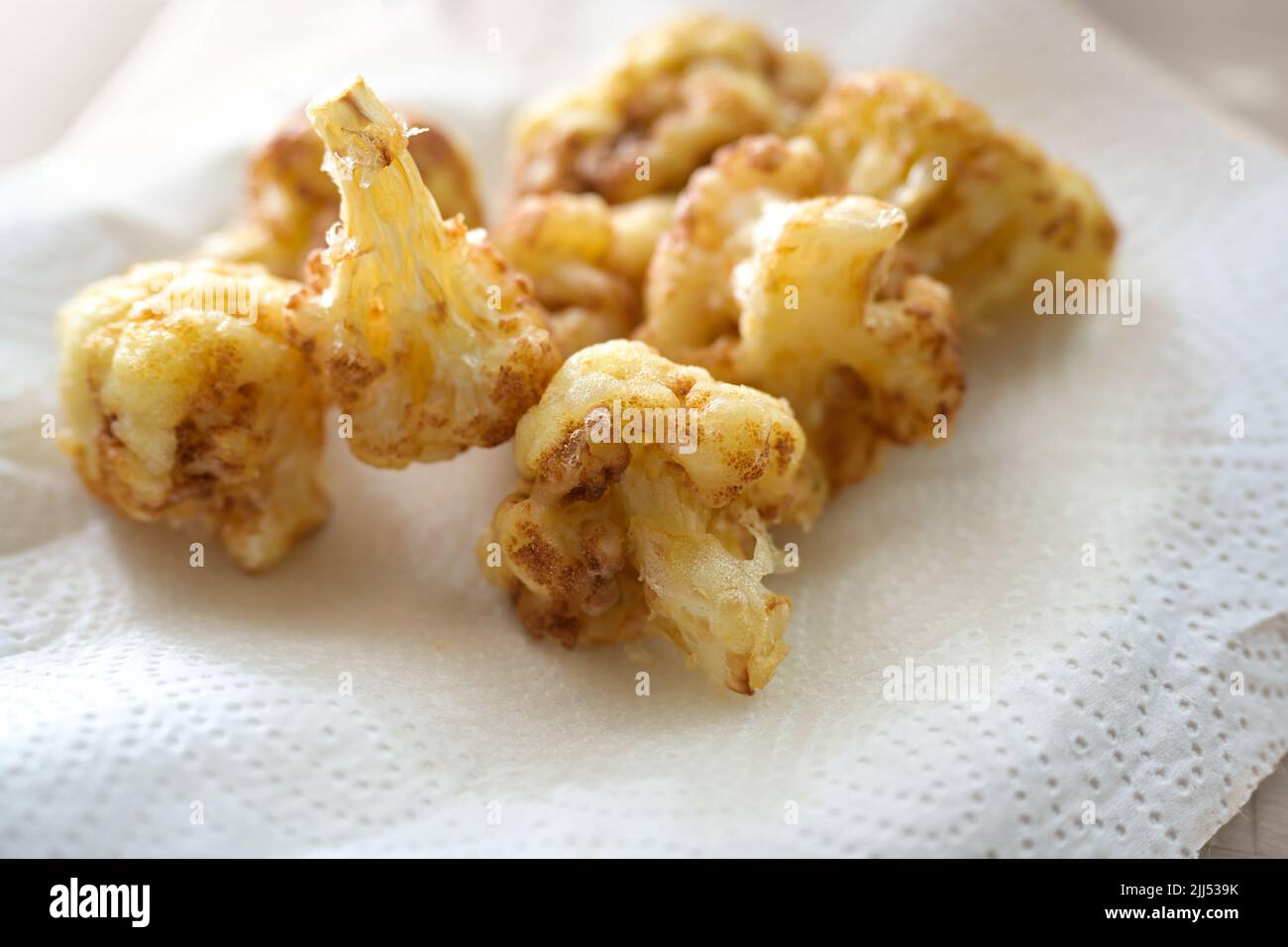 Goldene frittierte Blumenkohlröschen auf einem Papiertuch zum Abtropfen, kreatives Kochen mit Gemüse-Kopierraum, ausgewählter Fokus, enge Schärfentiefe Stockfoto