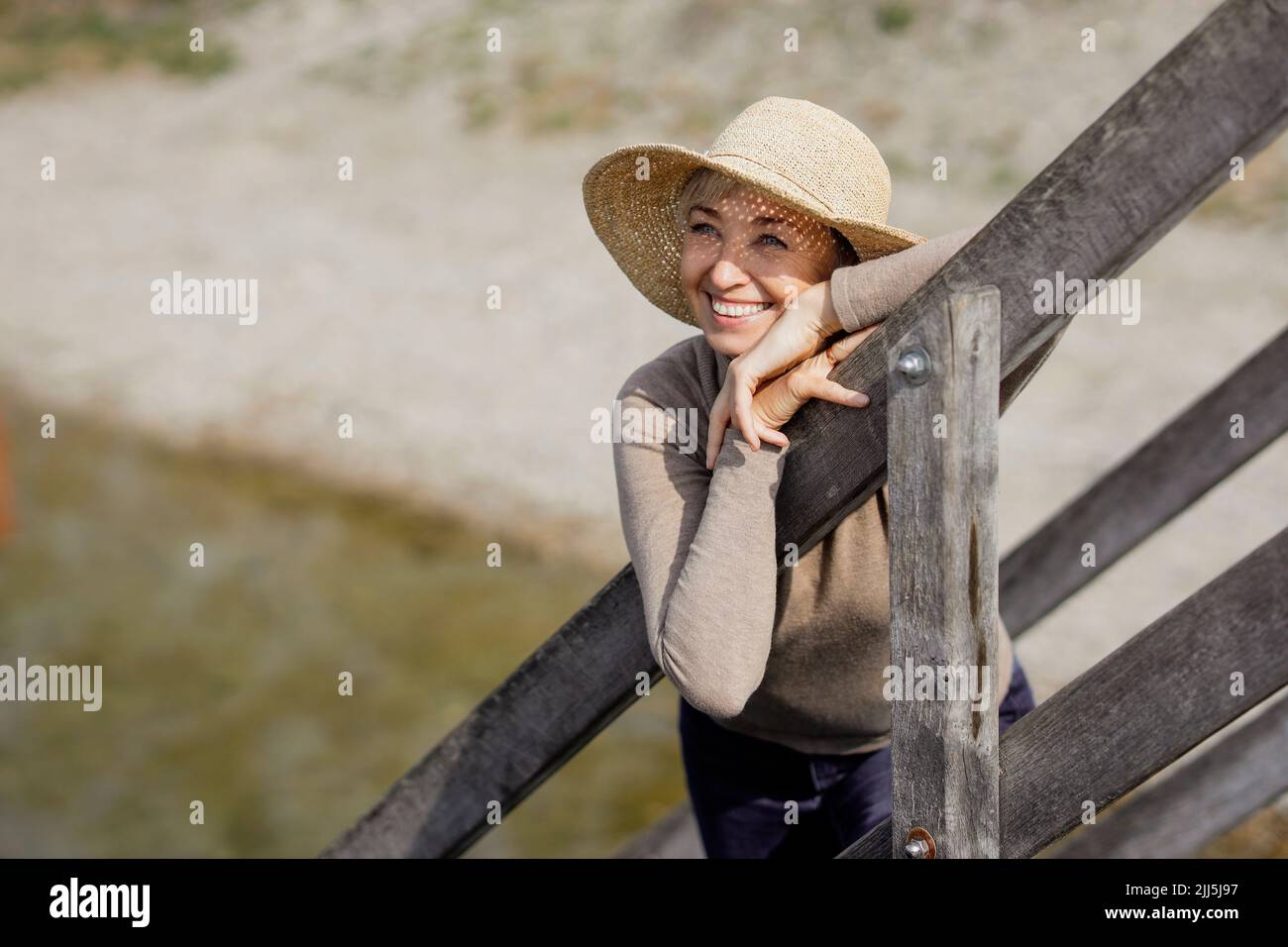 Lächelnde Frau mit Hut am Geländer Stockfoto