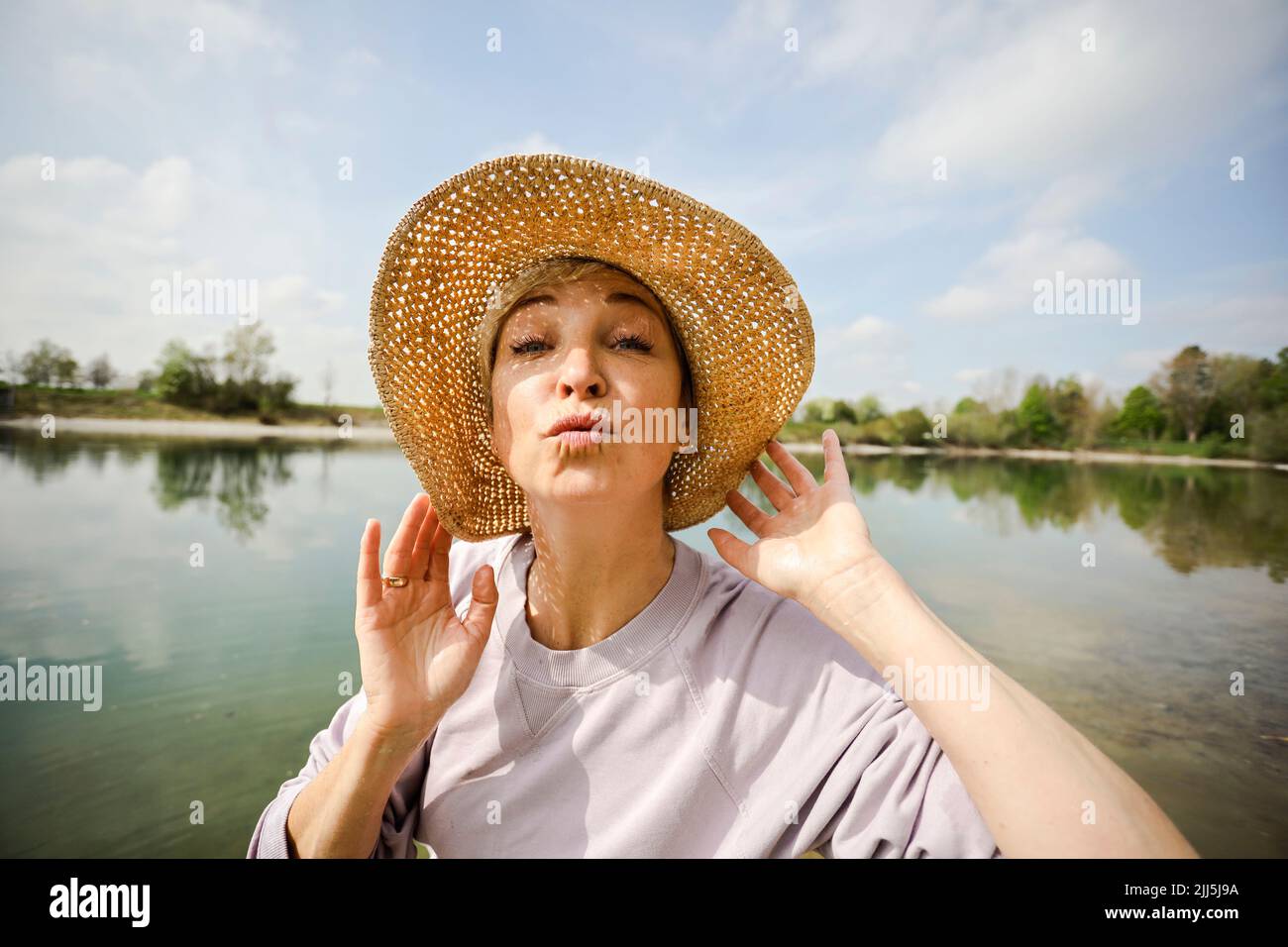 Reife Frau trägt Hut machen Puckering Lippen an sonnigen Tag Stockfoto