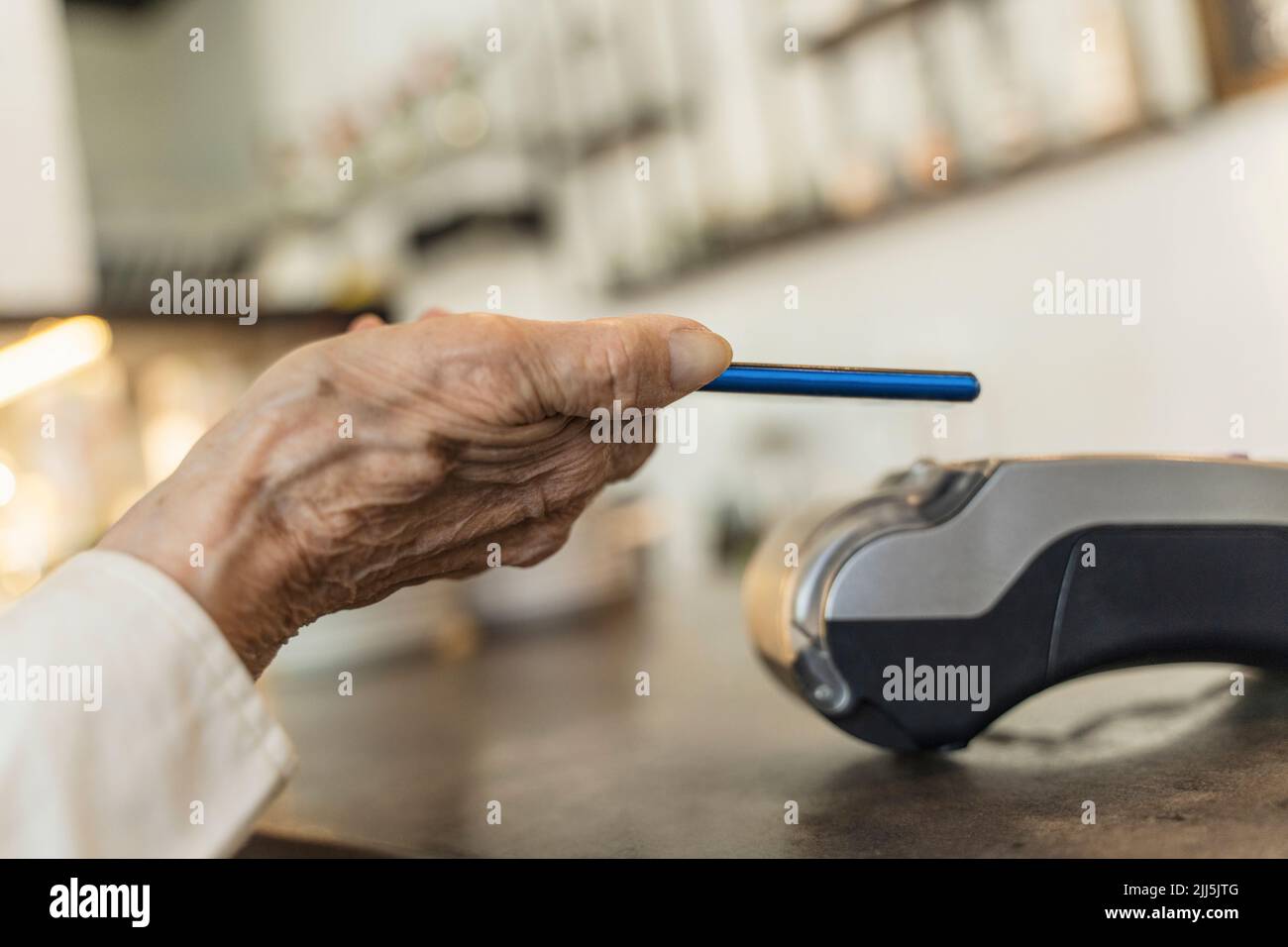Hand einer älteren Frau, die im Café über ein Smartphone bezahlt hat Stockfoto
