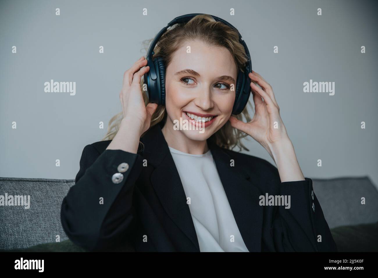 Besinnliche Geschäftsfrau mit kabellosen Kopfhörern Stockfoto