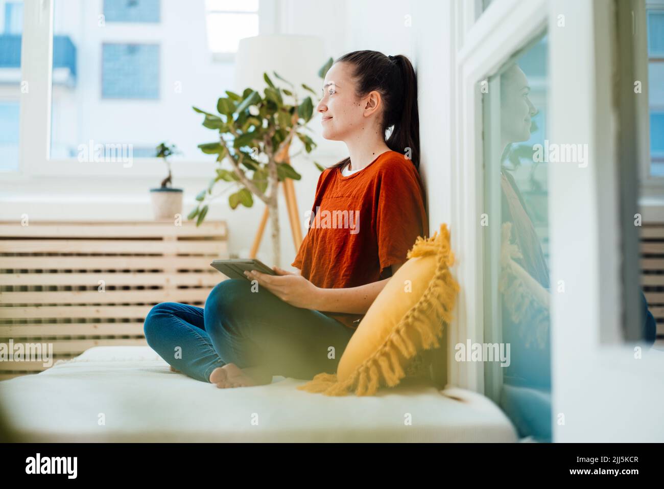 Durchdachte Frau mit Tablet-PC im Wohnzimmer Stockfoto