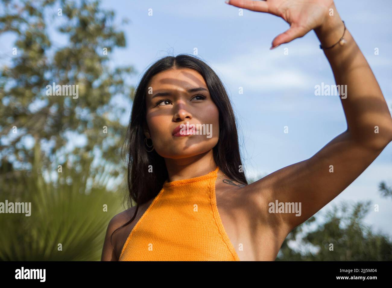 Junge Frau, die das Gesicht vor Sonnenlicht schützt Stockfoto