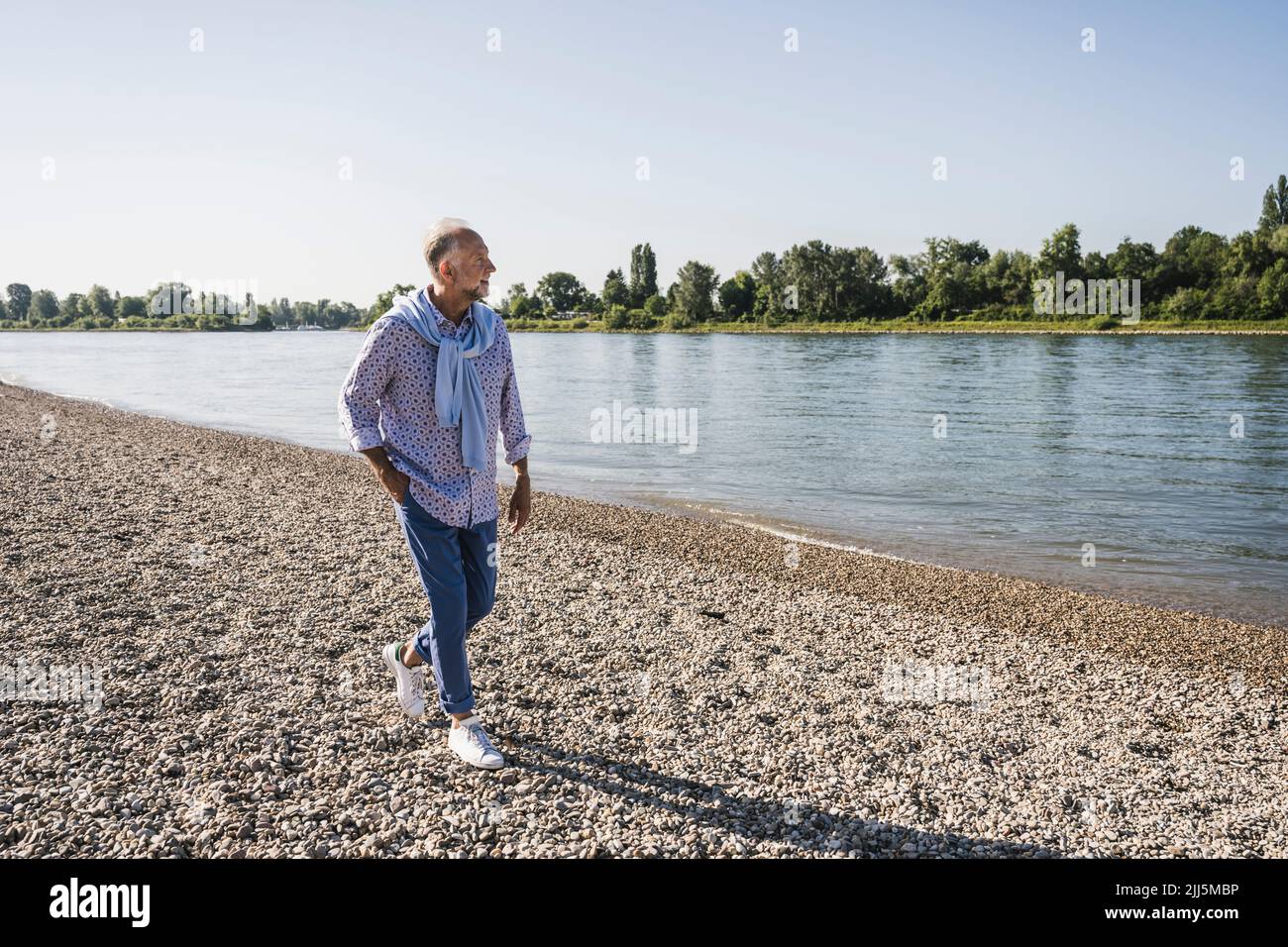 Mann mit den Händen in der Tasche beim Spazierengehen am Flussufer Stockfoto