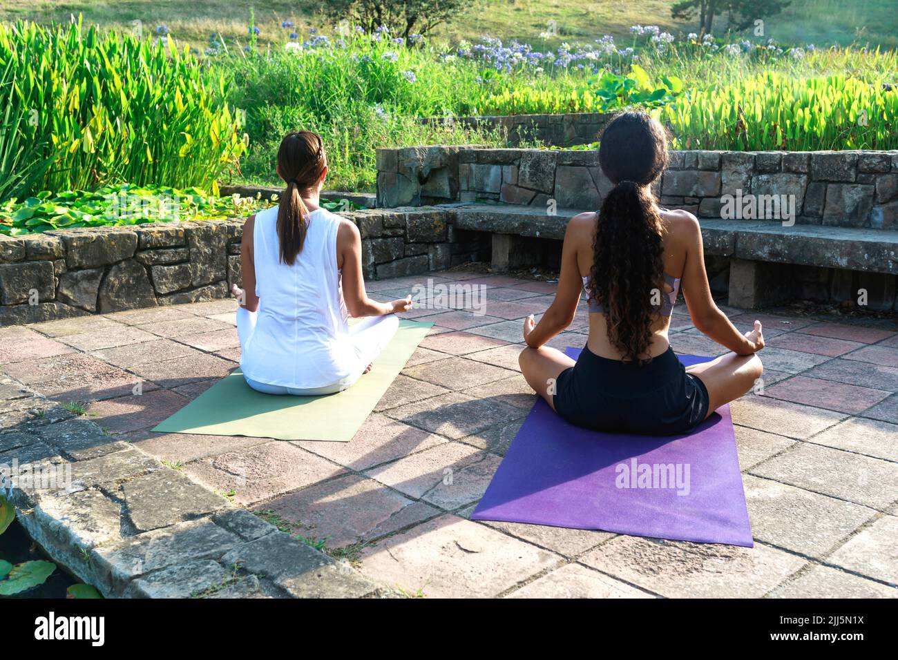Mädchen mit Yogalehrer meditiert im Park Stockfoto