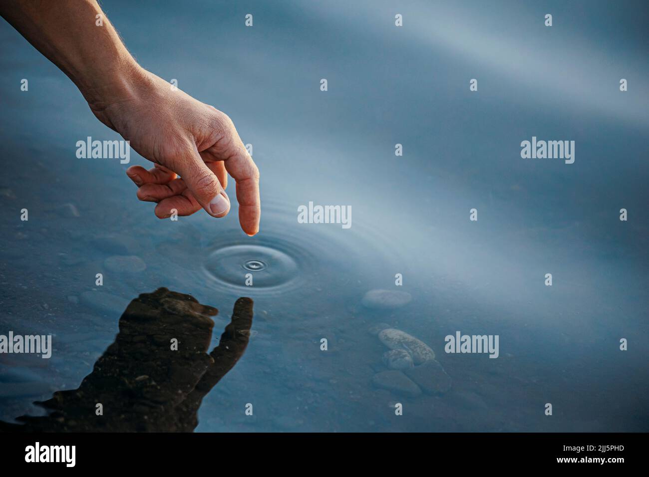 Hand eines Menschen, der das Meerwasser berührt Stockfoto