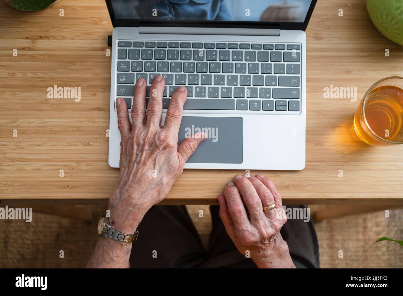 Hände einer älteren Frau, die zu Hause einen Laptop benutzt Stockfoto