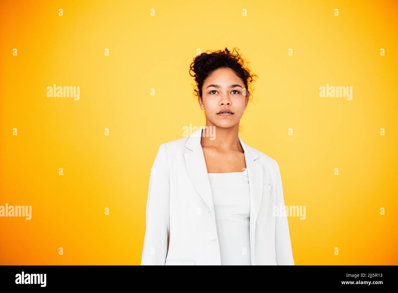 Junge Frau, die vor gelbem Hintergrund steht Stockfoto