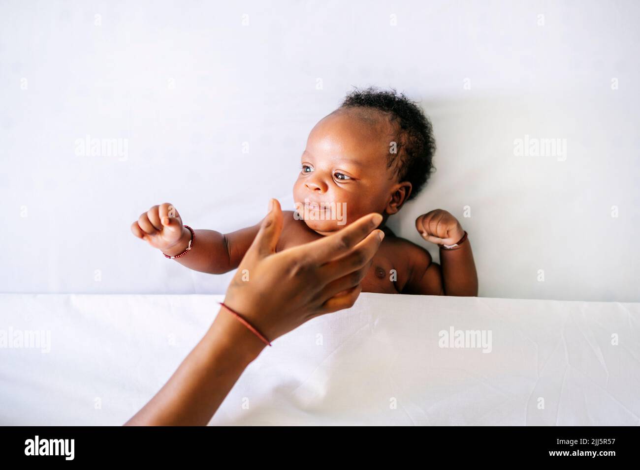 Die Hand der Mutter erreicht den Jungen, der zu Hause auf dem Bett liegt Stockfoto