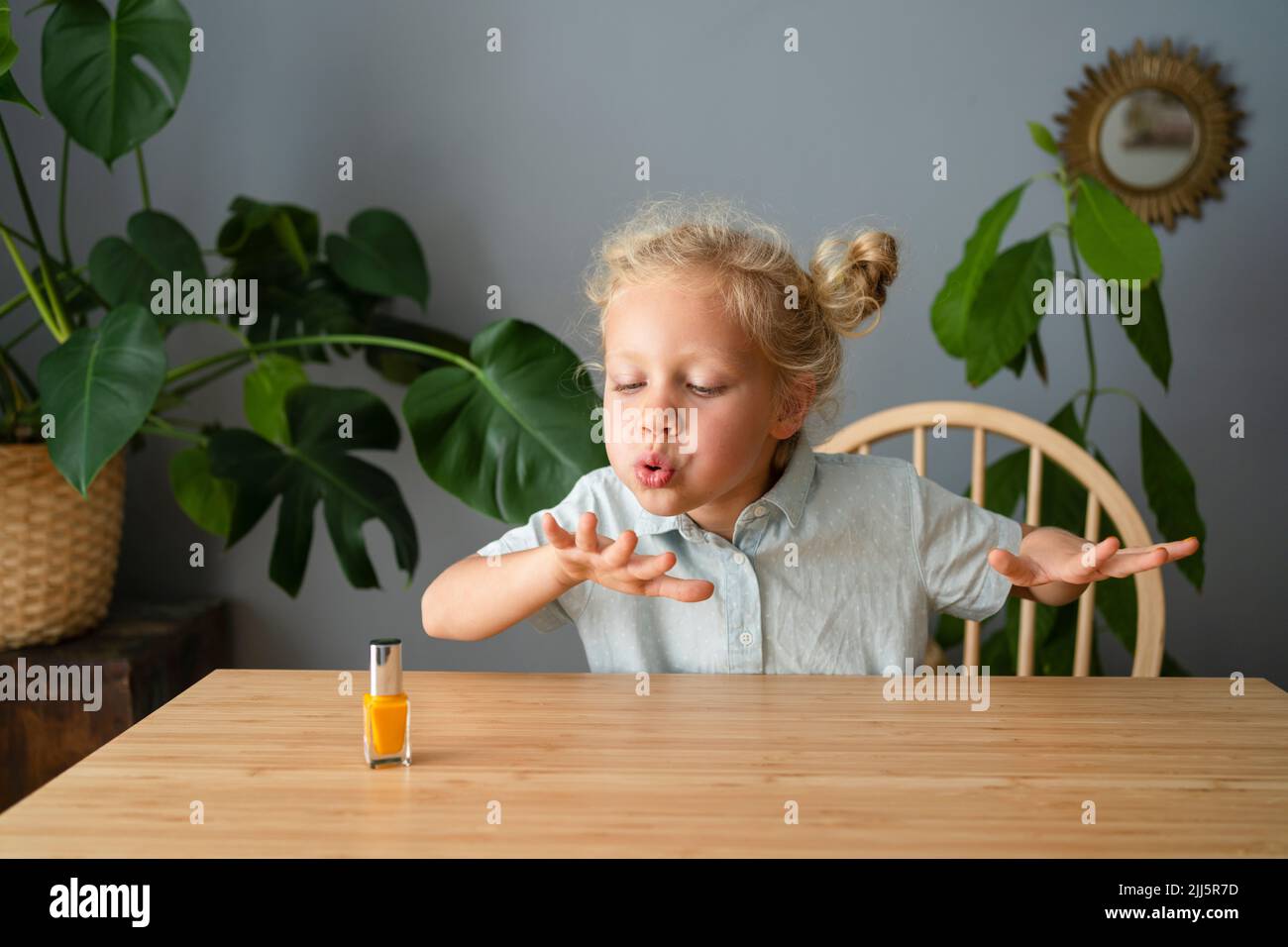 Mädchen weht auf lackierten Nägeln zu Hause sitzen Stockfoto
