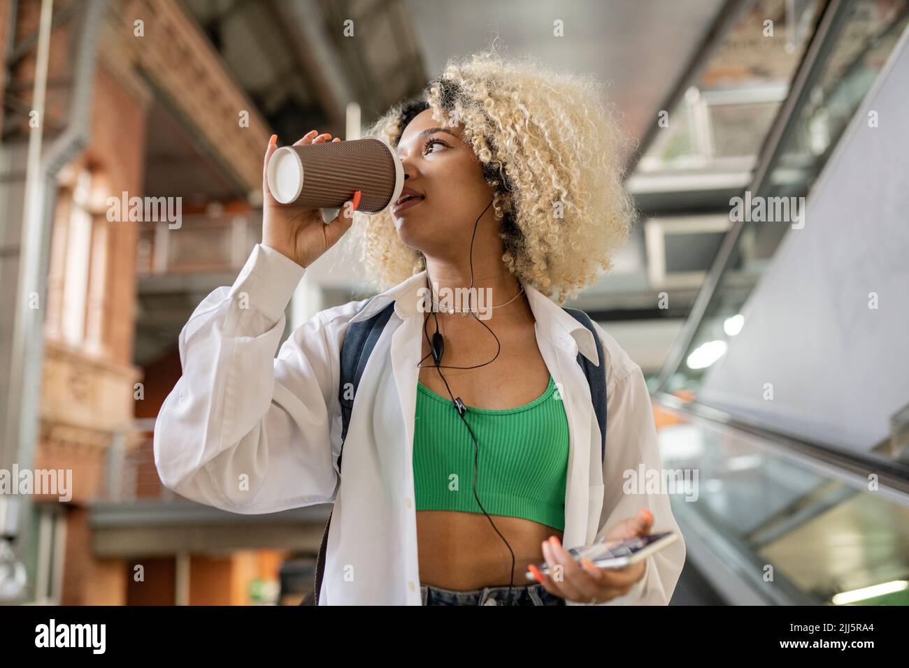 Kontemplative Frau trinkt Kaffee aus Einweg-Tasse Stockfoto