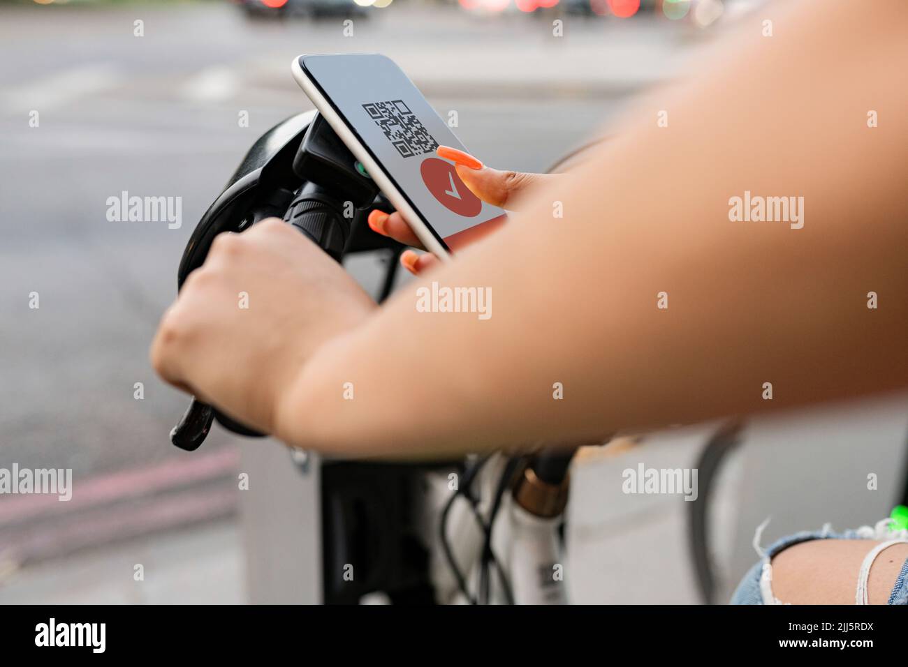 Frau scannt Barcode über Smartphone und mietet ein Elektrofahrrad Stockfoto