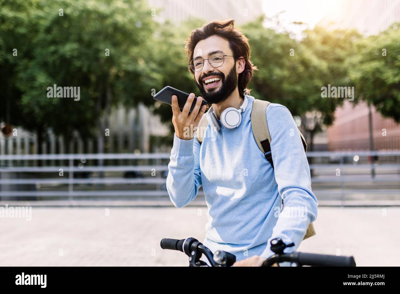 Lächelnder Mann mit kabellosen Kopfhörern, der auf einem Freisprechtelefon sprach Stockfoto