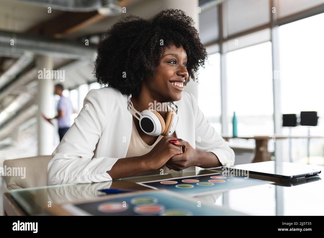 Geschäftsfrau mit kabellosen Kopfhörern am Schreibtisch Stockfoto