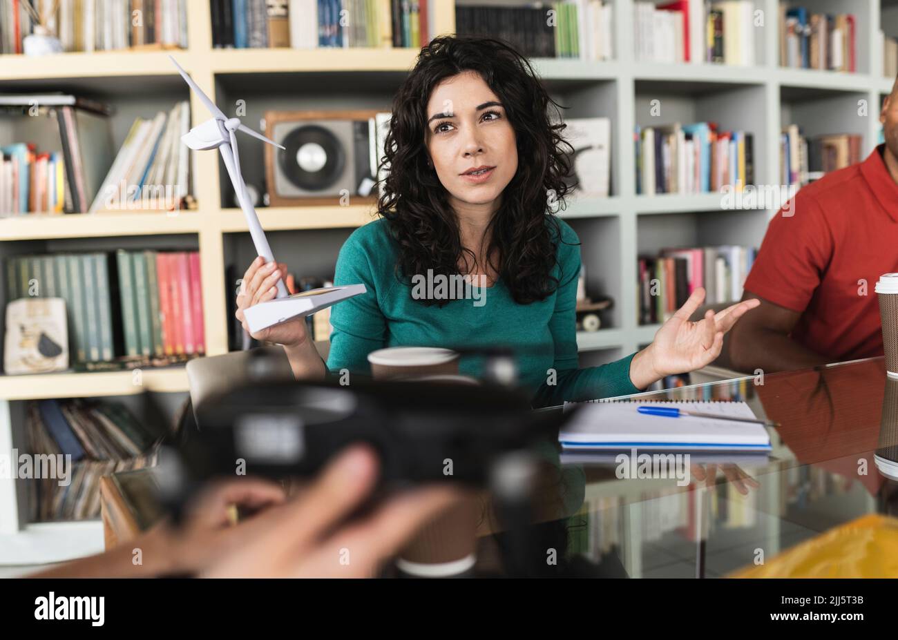 Geschäftsfrau mit Windturbinenmodell im Gespräch mit Kollegen im Büro Stockfoto