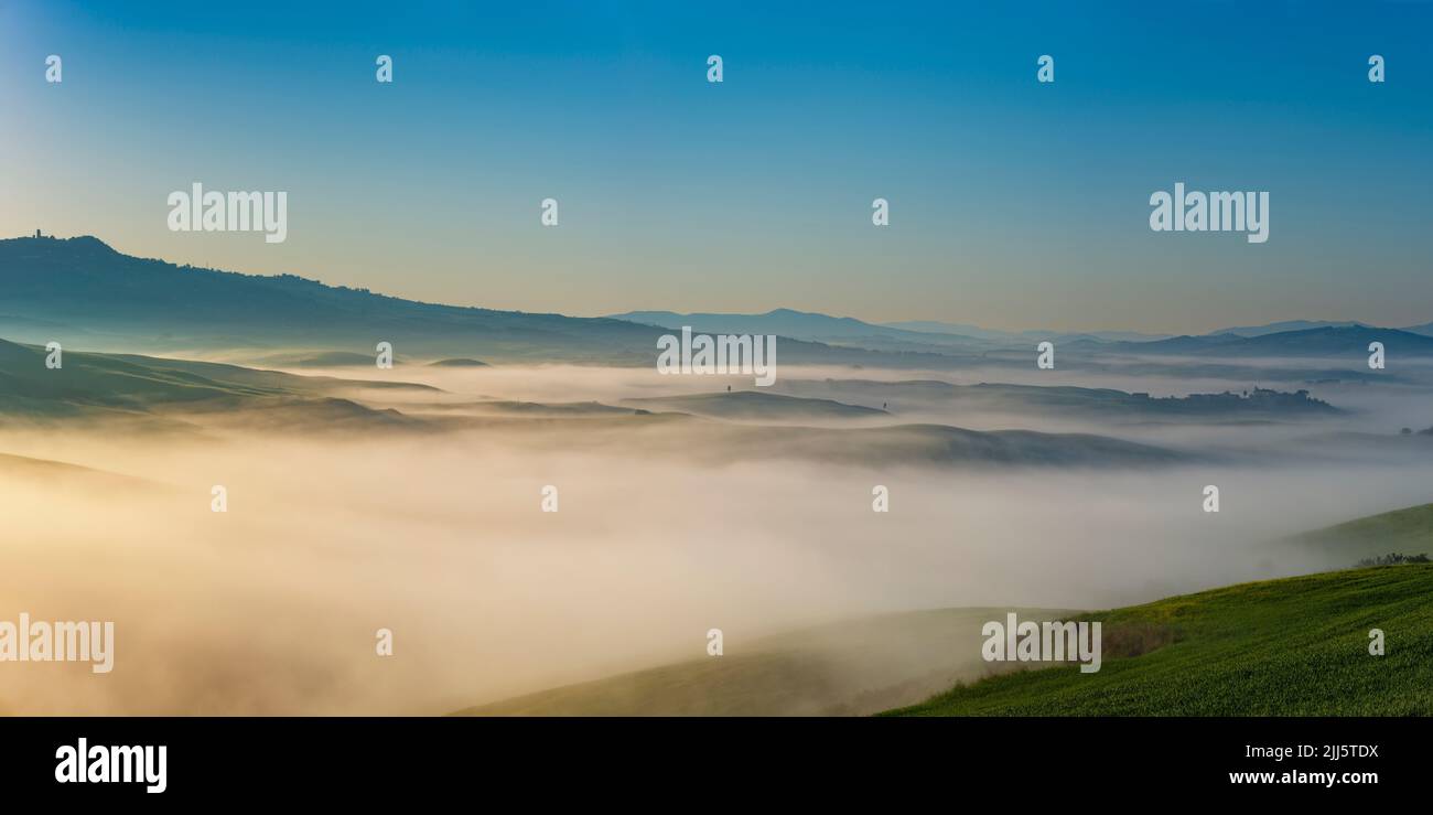 Italien, Toskana, Volterra, Panoramablick auf die hügelige Landschaft, die von dichtem Morgennebel umgeben ist Stockfoto