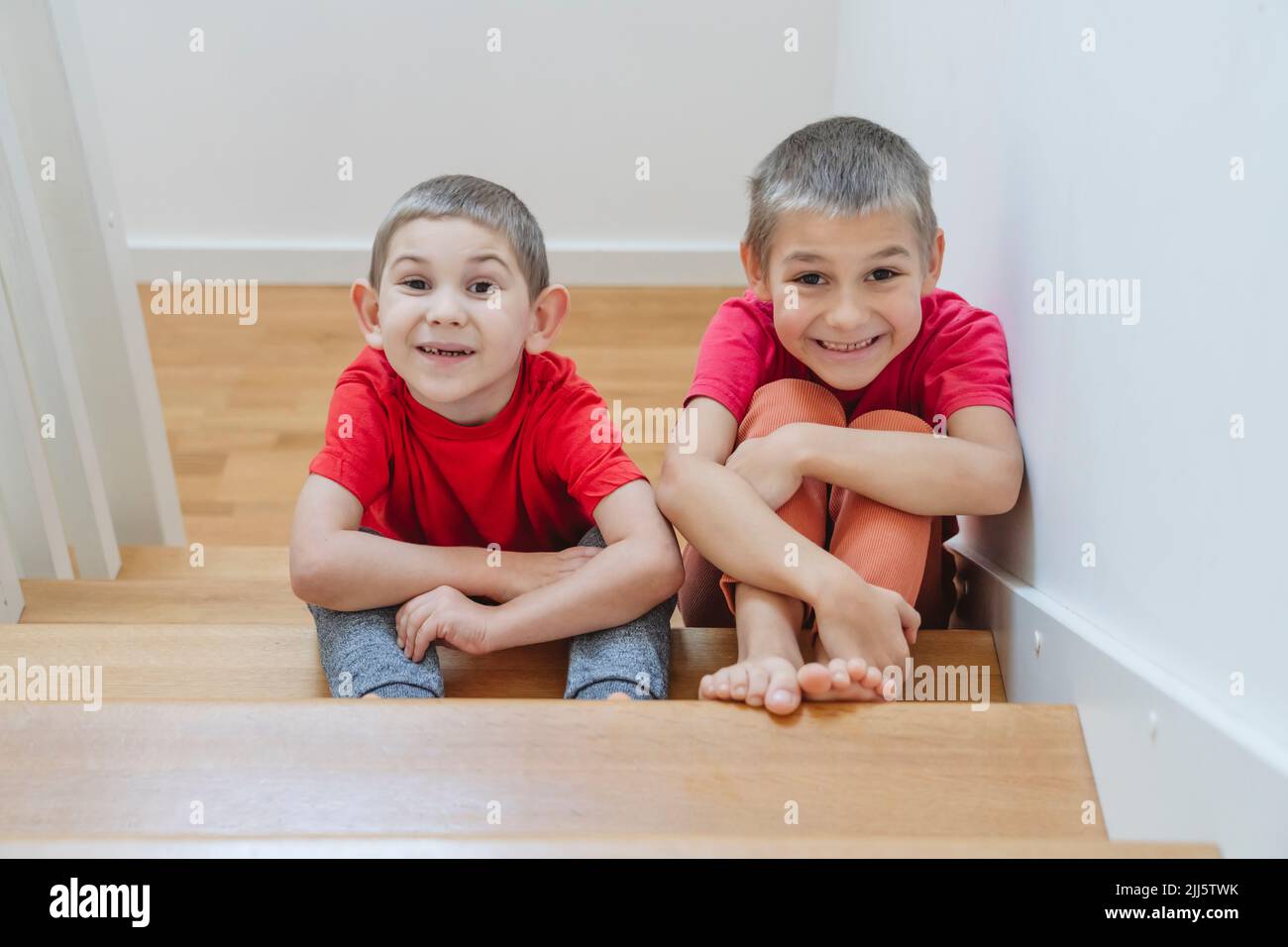 Lächelnde Brüder, die zu Hause auf der Treppe sitzen Stockfoto