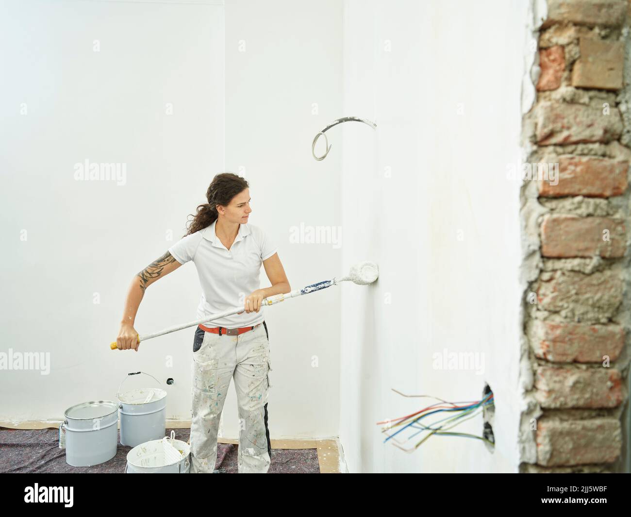 Maler mit Malerrolle, der das letzte Malen in der Wohnung macht Stockfoto