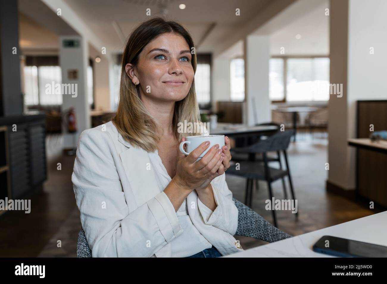 Lächelnde Geschäftsfrau mit Kaffeetasse im Restaurant Stockfoto