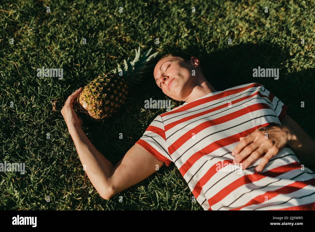 Frau, die sich im Park von Ananas auf Gras entspannt Stockfoto