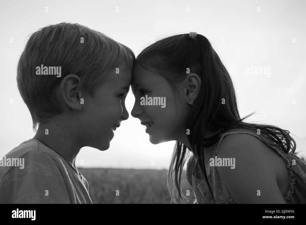 Schwarz-Weiß-Porträt von Mädchen und Jungen, Blick auf einander scharf, drücken ihre Stirn eins zu eins. Familie, Freundschaft, Nachwuchs, Kindheit Stockfoto