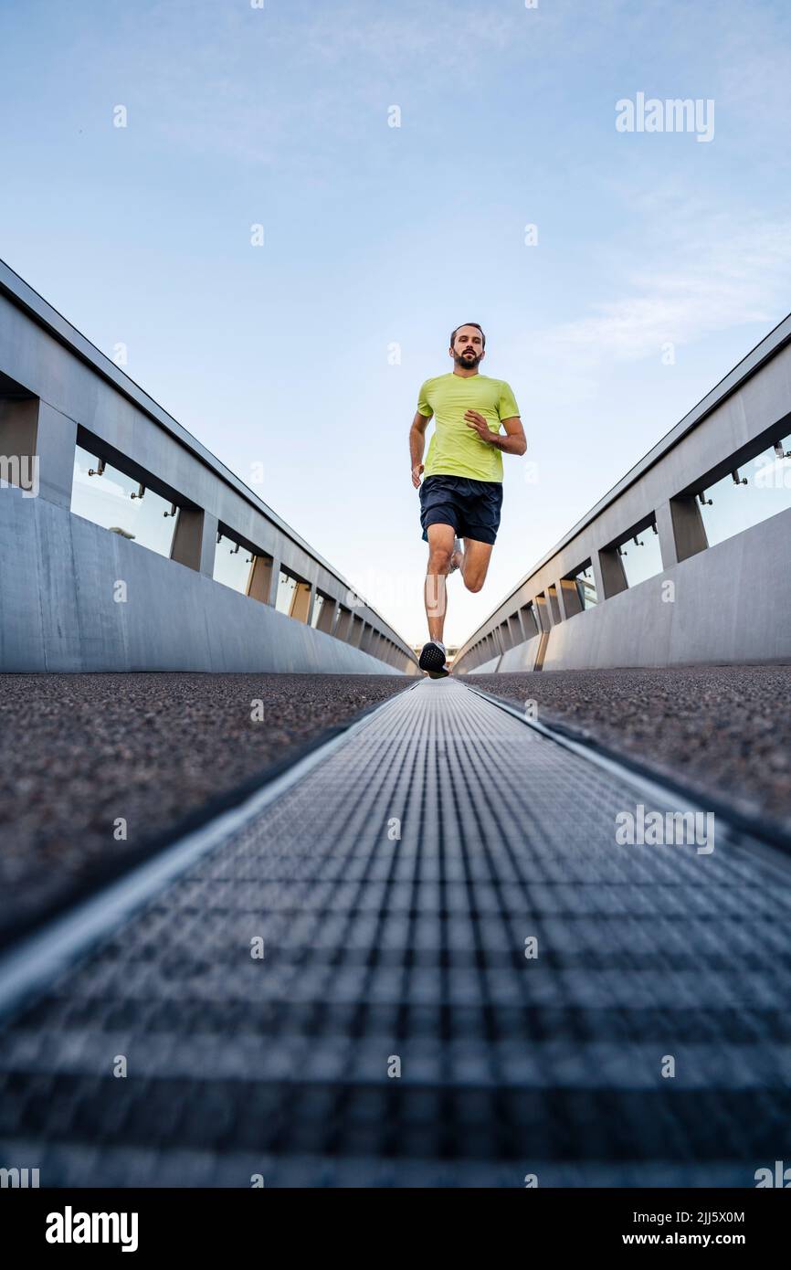 Junger Mann, der auf dem Gehweg läuft Stockfoto