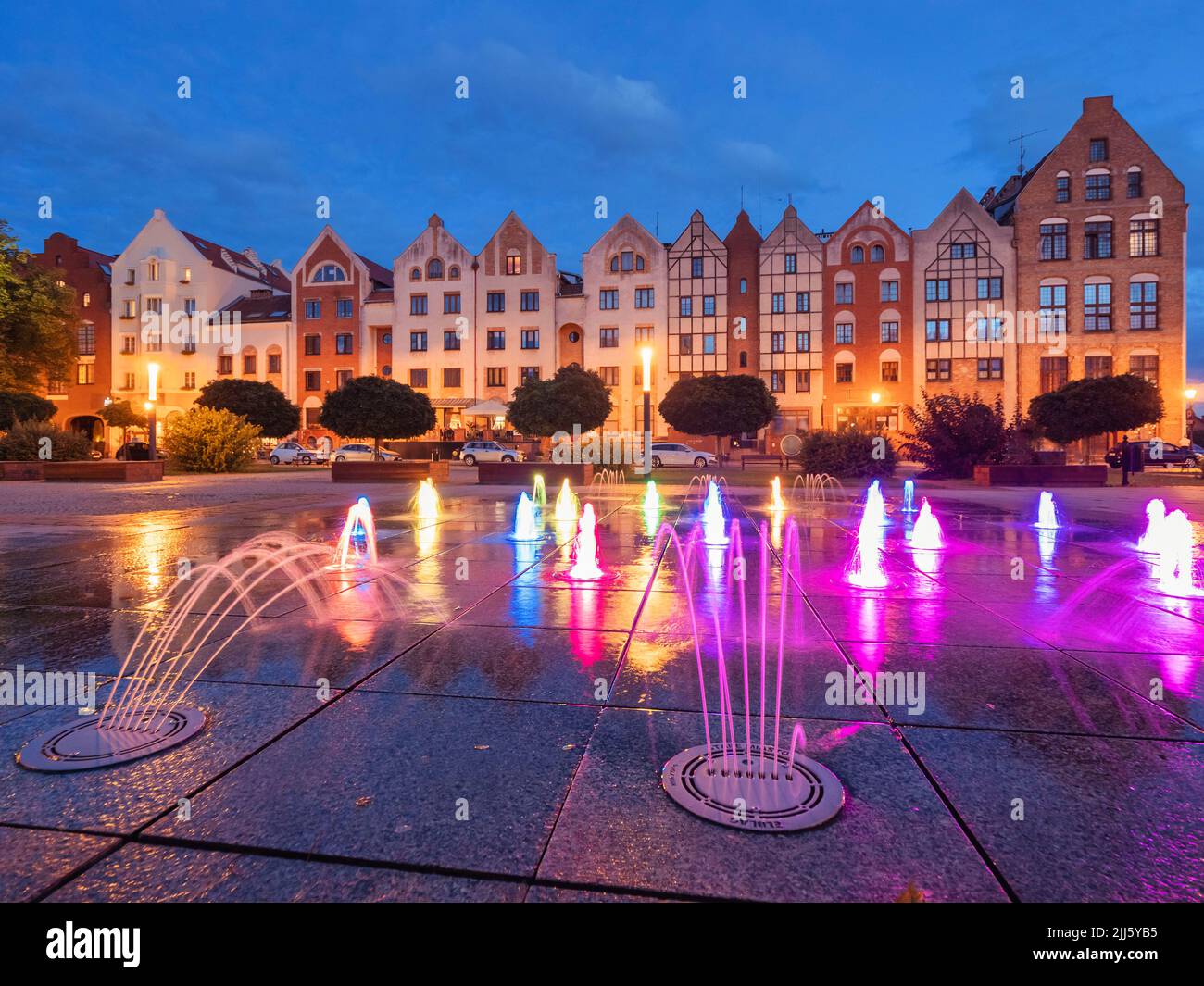 Polen, Woiwodschaft Warmian-Masuren, Elblag, farbenprächtiger Brunnen am Altstadtplatz mit Rosenhäusern im Hintergrund Stockfoto