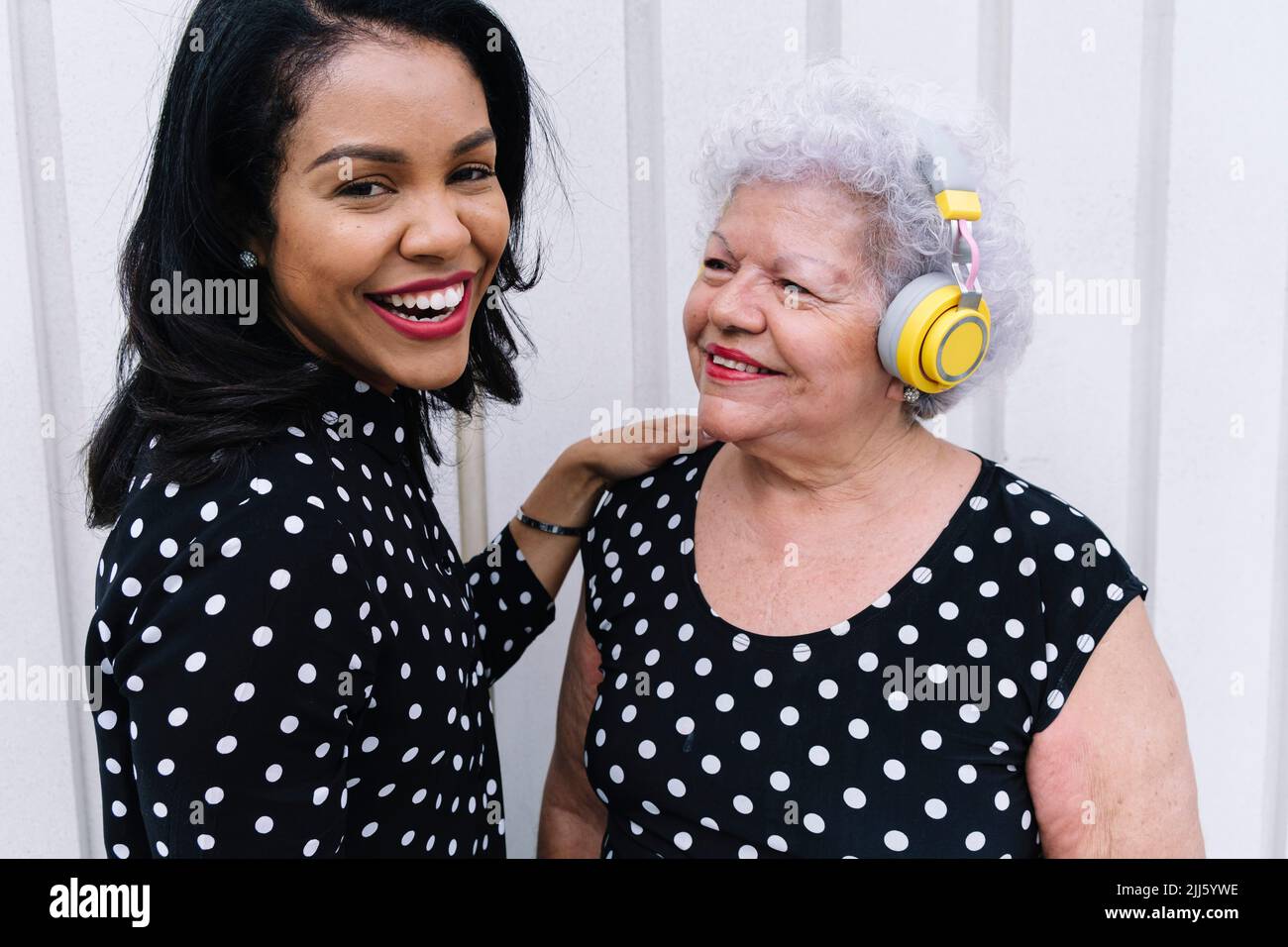 Glückliche ältere Frau mit kabellosen Kopfhörern, die ihre Tochter ansieht Stockfoto